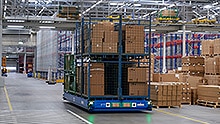 A fully loaded transport platform moves autonomously through a warehouse.