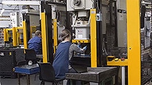 Zwei Werker arbeiten an manuellen Einlegepressen.